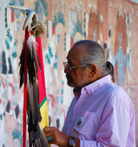 Man with staff looking at wall in grief